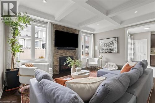 Spacious living area featuring a stone-clad fireplace, coffered ceiling, recessed lighting, wood-finish flooring, and ample natural light from large windows - 96 Damselfly Way, Ottawa, ON - Indoor Photo Showing Living Room With Fireplace