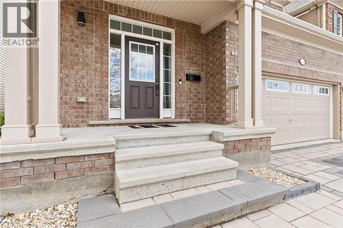 Brick exterior with a covered porch entry, featuring a dark brown front door with sidelights and transom windows - 96 Damselfly Way, Ottawa, ON - Outdoor With Exterior