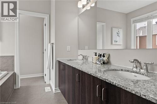 Dual vanity with wood-finish cabinetry and granite-style countertops, set against a full-width mirror - 96 Damselfly Way, Ottawa, ON - Indoor Photo Showing Bathroom