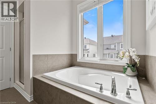Soaking tub with chrome fixtures, integrated into a tiled surround - 96 Damselfly Way, Ottawa, ON - Indoor Photo Showing Bathroom