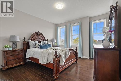 Hardwood-finish flooring featuring three individual windows with light blue drapery - 96 Damselfly Way, Ottawa, ON - Indoor Photo Showing Bedroom