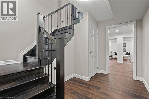 Dark wood-finish staircase with wrought iron balusters and light neutral walls - 96 Damselfly Way, Ottawa, ON - Indoor Photo Showing Other Room