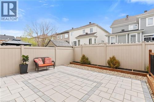 Paved outdoor space featuring a large patio, light-toned privacy fencing, and a raised garden bed with decorative rocks and plantings - 96 Damselfly Way, Ottawa, ON - Outdoor