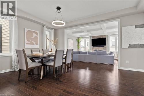Open-concept dining area featuring dark wood-finish flooring, a contemporary circular chandelier, and light gray walls - 96 Damselfly Way, Ottawa, ON - Indoor Photo Showing Dining Room