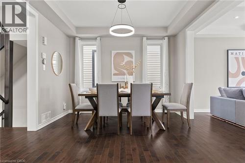 Dining area featuring dark wood-finish flooring, a contemporary circular pendant light, and tray ceiling detailing - 96 Damselfly Way, Ottawa, ON - Indoor Photo Showing Other Room