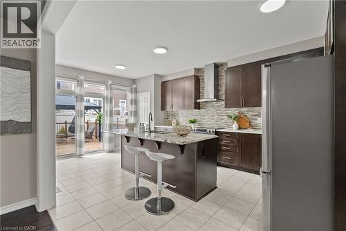 Kitchen featuring a central island with countertop seating, dark wood cabinetry, stainless steel appliances, and a tiled backsplash - 96 Damselfly Way, Ottawa, ON - Indoor Photo Showing Other Room