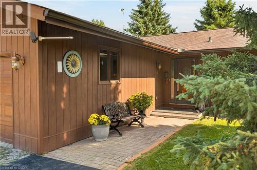 Brown vertical siding exterior with a shingled roof, a paved walkway, and a glass-paneled entry door - 12613 Second Line, Milton, ON - Outdoor
