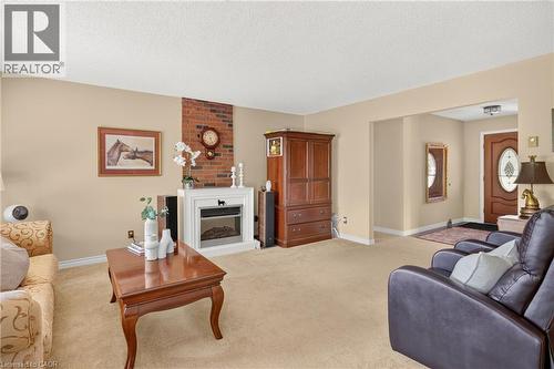 Living area featuring a brick accent wall with a white mantel and an electric fireplace insert - 12613 Second Line, Milton, ON - Indoor Photo Showing Living Room With Fireplace
