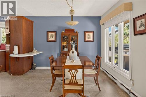 Dining area featuring tiled flooring, a multi-pane window with a light-filtering shade, and a built-in wood-finish cabinet with a white countertop extension - 12613 Second Line, Milton, ON - Indoor Photo Showing Dining Room