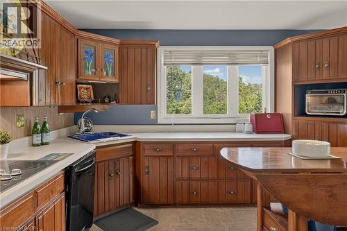 U-shaped kitchen featuring wood cabinetry, white countertops, a black built-in dishwasher, and a double window - 12613 Second Line, Milton, ON - Indoor Photo Showing Kitchen