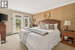 Private balcony access from a spacious room featuring a neutral carpet, textured wallcovering, and a classic wood headboard - 