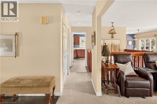 Hallway with light beige walls and neutral-toned carpeting, featuring a visible wooden railing - 12613 Second Line, Milton, ON - Indoor