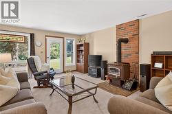 Living area featuring a brick accent wall with a wood-burning stove, white trim, stained glass window detail, and access to exterior - 