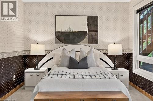 Carpeted room featuring a large window, patterned wallpaper, wood baseboards, and built-in bedside cabinets - 12613 Second Line, Milton, ON - Indoor Photo Showing Bedroom