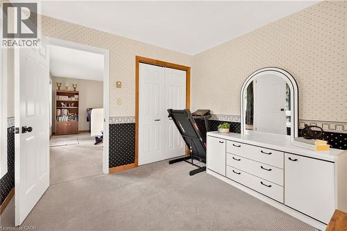 Carpeted room featuring a white paneled door, bi-fold closet doors with wood trim, and patterned wallpaper - 12613 Second Line, Milton, ON - Indoor