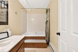 Bathroom featuring a built-in tub with tile surround, wood-finish paneling, and a shower curtain rod - 