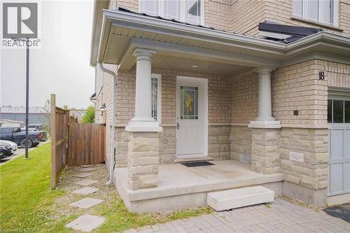 Front entry featuring a covered porch with stone-clad columns, a main door with decorative glass, and brick and stone veneer exterior - 18 Heritage Drive, Guelph, ON - Outdoor