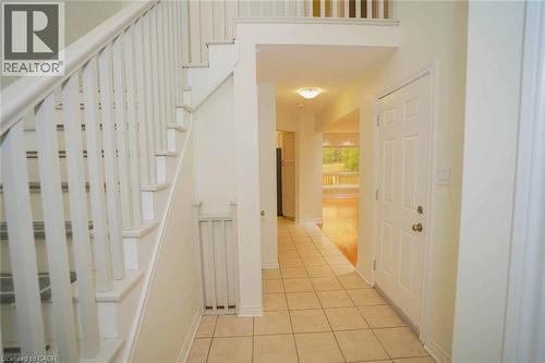 Foyer showcasing a white paneled door, a white painted staircase with matching balusters, and square tile flooring - 18 Heritage Drive, Guelph, ON - Indoor Photo Showing Other Room