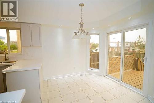 Bright dining area featuring a sliding glass door to a wooden deck, ceramic tile flooring, and a contemporary chandelier - 18 Heritage Drive, Guelph, ON - Indoor Photo Showing Other Room