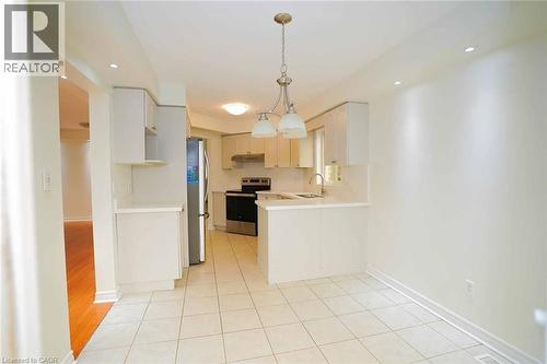 Bright kitchen and dining area featuring white cabinetry, stainless steel appliances, a double basin sink, and recessed lighting - 18 Heritage Drive, Guelph, ON - Indoor Photo Showing Kitchen