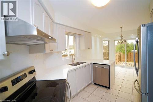 Kitchen featuring white cabinetry, light-toned countertops, tile flooring, and stainless steel appliances - 18 Heritage Drive, Guelph, ON - Indoor Photo Showing Kitchen With Double Sink With Upgraded Kitchen