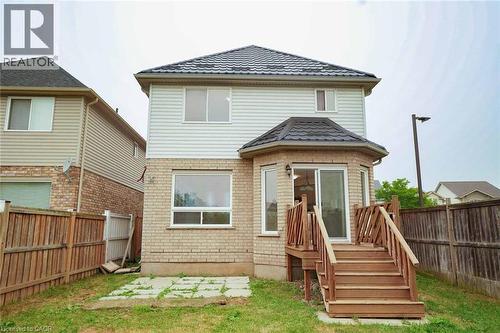 Rear exterior featuring a brick and siding facade, multi-level deck with wood railings, sliding glass patio door, and bay window - 18 Heritage Drive, Guelph, ON - Outdoor