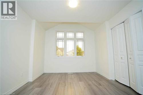 Room featuring wood-finish flooring, a multi-pane window, white walls, and bi-fold closet doors - 18 Heritage Drive, Guelph, ON - Indoor Photo Showing Other Room