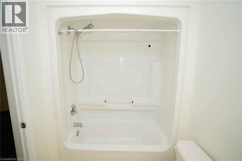 White fiberglass tub and shower combination with chrome fixtures, an integrated soap dish, and a handheld shower head - 18 Heritage Drive, Guelph, ON - Indoor Photo Showing Bathroom