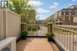 Outdoor terrace featuring wood-finish decking, a privacy fence, and an ornate metal railing - 