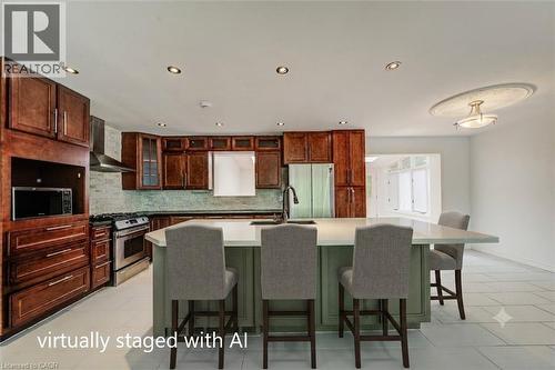 Kitchen featuring an expansive island with countertop seating, rich wood cabinetry, stainless steel appliances, a modern range hood, and light-toned tile flooring - 109 White Oak Place, Waterloo, ON - Indoor