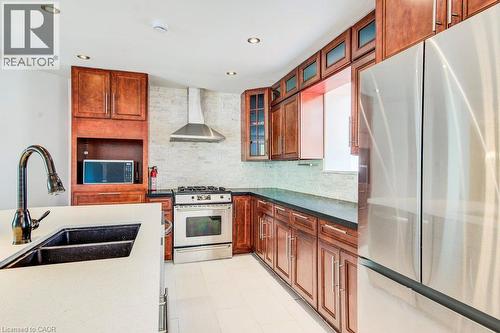 Kitchen featuring wood cabinetry, stainless steel appliances, a white solid surface countertop, and a black double basin sink - 109 White Oak Place, Waterloo, ON - Indoor Photo Showing Kitchen With Double Sink