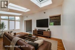 Living area featuring multiple skylights, large multi-pane windows with blinds, and wood-finish flooring - 