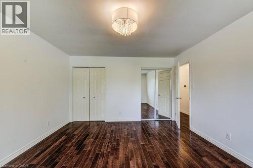 Room featuring dark wood-finish flooring, a contemporary drum chandelier, and light-toned walls - 109 White Oak Place, Waterloo, ON - Indoor Photo Showing Other Room