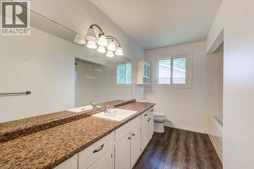 Bathroom featuring a double vanity with stone-look countertops, integrated sinks, white cabinetry, and wood-finish flooring - 109 White Oak Place, Waterloo, ON - Indoor Photo Showing Bathroom