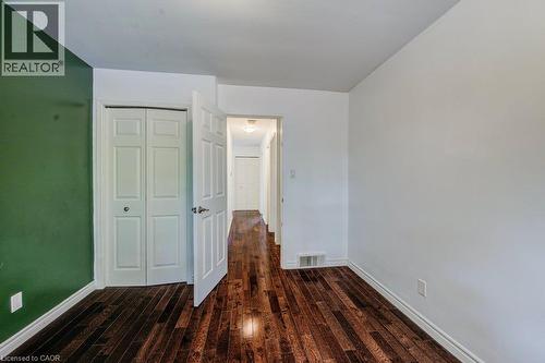 Room featuring rich wood-finish flooring, white baseboards, a bi-fold closet, and a hallway entry - 109 White Oak Place, Waterloo, ON - Indoor Photo Showing Other Room