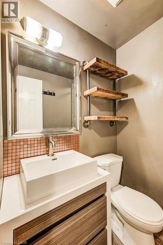 Bathroom vanity featuring a rectangular vessel sink, brushed nickel faucet, and a copper-toned mosaic tile backsplash - 109 White Oak Place, Waterloo, ON - Indoor Photo Showing Bathroom