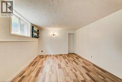 Spacious room featuring wood-finish flooring, white paneling, and a single window - 