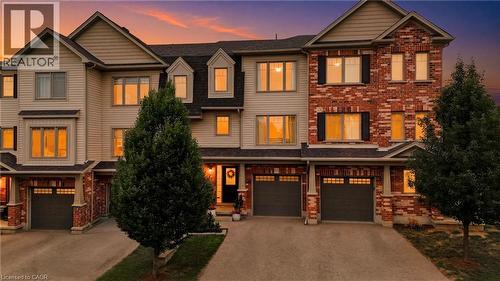 Red brick and beige siding townhome with multiple dormer windows, individual garages, and architectural shutters - 750 Lawrence Street Unit# 38, Cambridge, ON - Outdoor With Facade