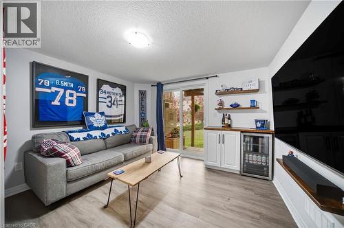 Spacious room featuring wood-finish flooring, a built-in wet bar with white cabinetry, and sliding glass door access to the exterior - 750 Lawrence Street Unit# 38, Cambridge, ON - Indoor Photo Showing Living Room