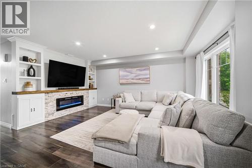 Spacious living area featuring dark wood-finish flooring, recessed lighting, and a built-in media console with open shelving and closed cabinetry - 750 Lawrence Street Unit# 38, Cambridge, ON - Indoor Photo Showing Living Room With Fireplace