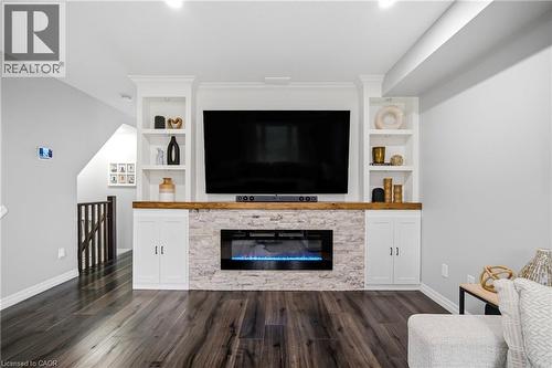 Media console featuring a stone-clad electric fireplace, built-in cabinetry, and integrated shelving - 750 Lawrence Street Unit# 38, Cambridge, ON - Indoor Photo Showing Living Room With Fireplace