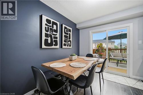 Dining area featuring a live-edge wood table, dark accent wall, and wood-finish flooring - 750 Lawrence Street Unit# 38, Cambridge, ON - Indoor Photo Showing Dining Room
