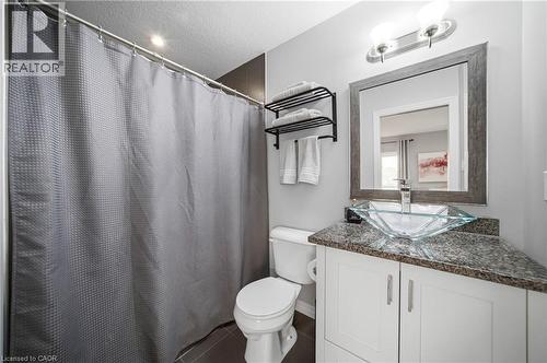 Bathroom vanity featuring a vessel sink, granite-style countertop, and white cabinetry - 750 Lawrence Street Unit# 38, Cambridge, ON - Indoor Photo Showing Bathroom