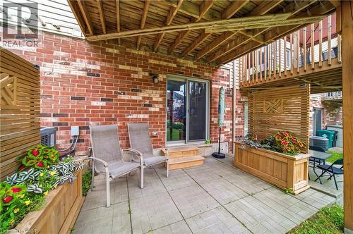 Paved patio area featuring brick exterior, wood-finish privacy screens, built-in planter boxes, and a sliding glass door entry - 750 Lawrence Street Unit# 38, Cambridge, ON - Outdoor With Deck Patio Veranda With Exterior