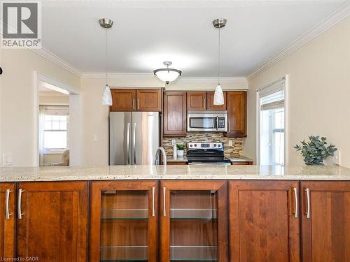 Kitchen featuring wood cabinetry, stainless steel appliances, and light-toned countertops - 656 Frank Place, Milton, ON - Indoor Photo Showing Kitchen With Upgraded Kitchen