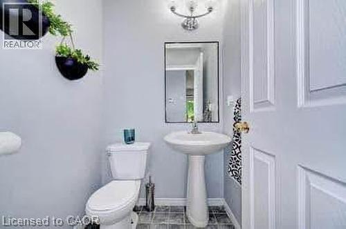 Pedestal sink and toilet with paneled door and overhead lighting - 175 David Bergey Drive Unit# L74, Kitchener, ON - Indoor Photo Showing Bathroom