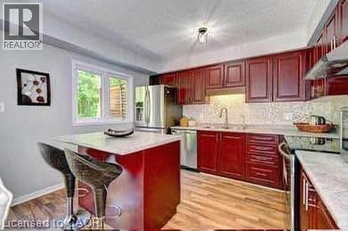Kitchen featuring wood-finish flooring, dark wood cabinetry, white countertops, stainless steel appliances, and a window with exterior views - 175 David Bergey Drive Unit# L74, Kitchener, ON - Indoor Photo Showing Kitchen