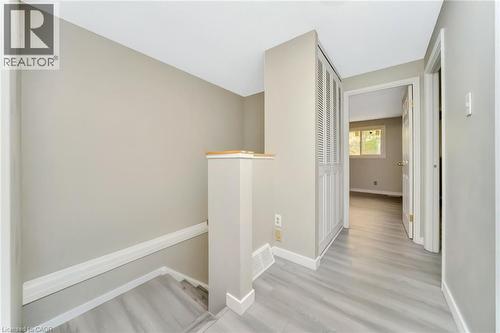 Upper-level hallway featuring light wood-finish flooring, a built-in louvered closet, and neutral wall paint - 53 Burns Drive, Guelph, ON - Indoor Photo Showing Other Room