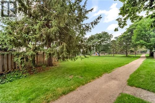 Expansive green space featuring a natural walking path, mature trees, manicured lawn, and a wooden privacy fence - 53 Burns Drive, Guelph, ON - Outdoor