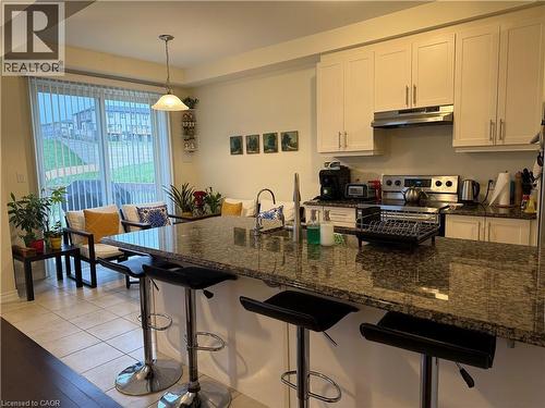 Kitchen island featuring a polished speckled countertop, integrated sink, and bar seating - 63 Ridge Road, Cambridge, ON - Indoor